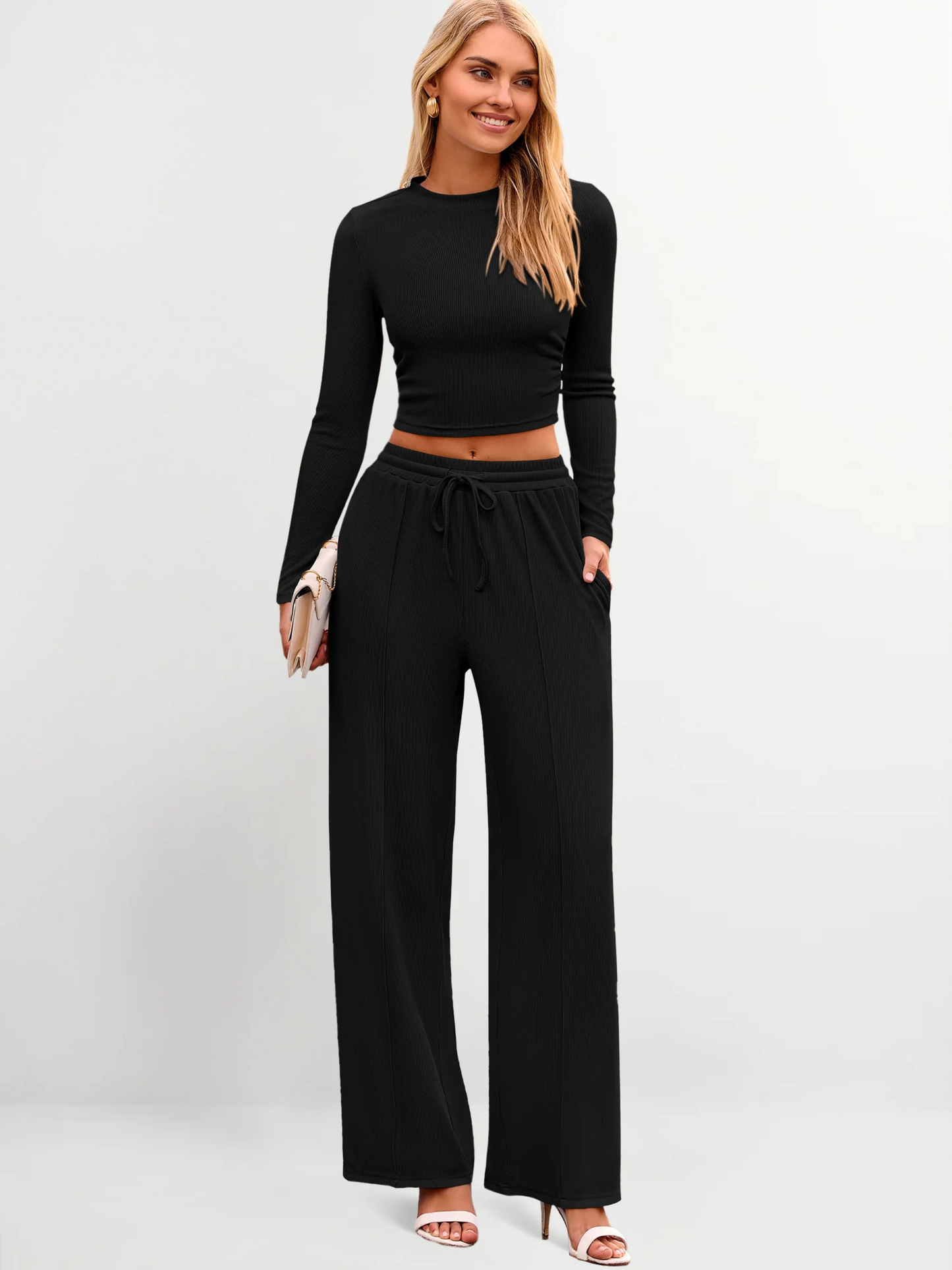 Woman wearing a black long-sleeve top and wide-leg pants on a white background